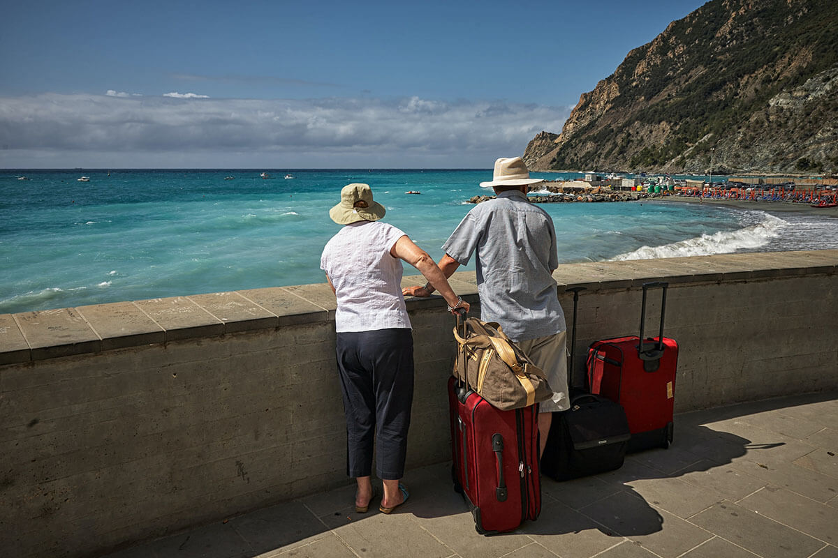 An old couple with their four luggage, looking at the ocean.